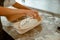 Woman makes decor on raw bread loaf in ceramic dish in craft bakery