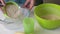 Woman makes dough for unleavened cakes. Pours flour into a glass container and adds a little water. Prepares unleavened bread