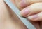 Woman makes herself a manicure at home, cuts her nails. Close-up. Nails cutting process. Nail file macro