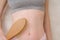 Woman makes massage stomach with wooden soft massage brush for body and legs