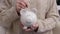 Woman makes savings puts money. Woman is putting coin into piggy bank