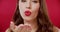 Woman, makeup and blow kiss in studio, face and lipstick for cosmetics with emoji by red background. Girl, model and