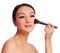 Woman with makeup brush. beautiful Asian brunette applying blush on her cheek, isolated