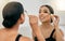 Woman, makeup and mascara in a mirror for beauty on her eye with a smile in a room. Young beautiful latino female with