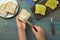 Woman making avocado sandwich at blue table, top view