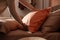 Woman making bed with fresh linens and orange pillow, closeup