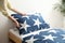 Woman making bed with stylish linens in children`s room, closeup