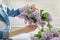 Woman making bouquet of lilac branches, close-up female arranging flowers bunch in vase