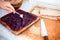 Woman making cake. Person hand with spoon spreads jam on sponge cake