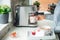 Woman making coffee on machine during preparing a surprise breakfast for lover on Valentines& x27; day. A tray with oatmeal