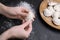 Woman making dumplings (varenyky) at black table, closeup