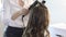 Woman making hairdressing for teen pretty girl with long hair.