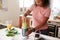 Woman Making Healthy Juice Drink With Fresh Ingredients In Electric Juicer After Exercise