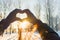 Woman making heart symbol with hands.sunny winter evening, sunrays, Valentines day, Love concept