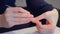 Woman is making manicure at home cutting cuticle using scissors, hands closeup.