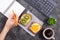 Woman making notes in notebook at lunch with fruit sandwiches and keyboard