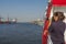 Woman is making photography from a ship of the modern cargo port with many container cranes in Hamburg harbor at Elbe river,