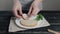 Woman making sandwich from bread, boiled chicken breast, green fresh parsley and bites it.