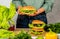 Woman is making tasty burger with cutlet, chesse and vegetables in the kitchen.