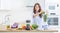 Woman making vegetable soup or smoothies with blender in her kitchen. Young happy woman preparing healthy drink with spinach