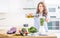 Woman making vegetable soup or smoothies with blender in her kitchen. Young happy woman preparing healthy food or drink with olive