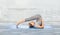 Woman making yoga in plow pose on mat outdoors