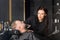 woman male master hairdresser is trimming man\'s beard with scissors