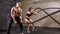 Woman and man couple training together doing battling rope workout