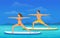 Woman and Man doing Stand Up Paddling Yoga on Paddle Board at Seaside