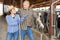 Woman and man farmers friendly talking during work in cowshed