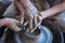 Woman and man hands. Potter at work. Creating dishes. Potter`s wheel. Dirty hands in the clay and the potter`s wheel