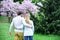 Woman and man hug in blossoming garden, back view