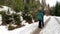 Woman and man in jackets walk in the winter through a snowy forest