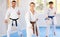 Woman and man in kimono standing in fight stance during group karate training in gym