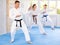 Woman and man in kimono standing in fight stance during group karate training in gym