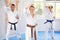Woman and man in kimono standing in fight stance during group karate training in gym
