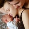 Woman and man lie on bed together with newborns. Mom, dad and baby. Boy clung to his mother. Portrait of young smiling family with