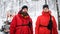 Woman and man paramedic from mountain rescue service outdoors in winter in forest, looking at camera.