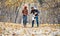 Woman and man petting the dog walking her in a colorful fall setting