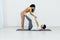 a woman and a man practice a paired yoga asana in a white room