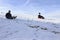 A woman and a man riding a snowmobile down a mountain in winter