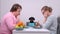 Woman and man sit at the table together with dog, having vegetarian breakfast