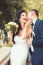 Woman and man smile on wedding day. Groom kiss happy bride with bouquet. Wedding couple in love. Newlywed couple on