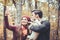 Woman and man with their dog on autumn walk taking a phone selfie