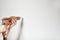 Woman with manicured hands drilling a white wall with an orange power drill