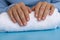 Woman manicured hands, stylish beige nails. Closeup of manicured nails of female hand in blue sweater in blue background