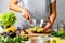 Woman mashing avocado with a fork, cooking guacamole in a glass bowl. healthy food concept.