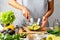 Woman mashing avocado with a fork, cooking guacamole in a glass bowl. healthy food concept.