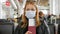 A woman in a mask at the airport with a passport and a plane ticket in her hands