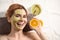 Woman with mask on face and cut orange relaxing in spa salon. Space for text